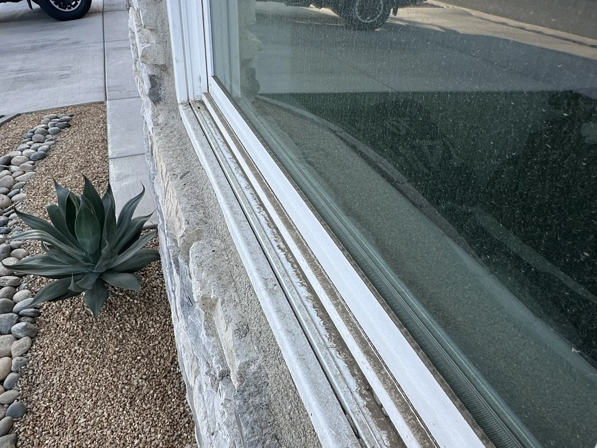 Before: a spotted front window with a gritty sill track