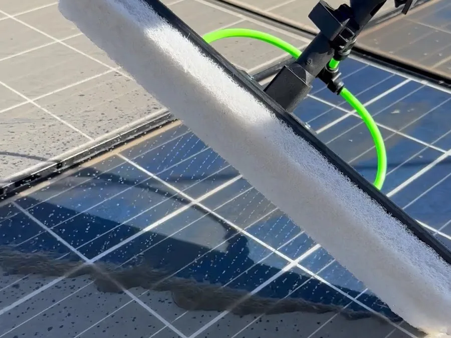 Soft brush on a water-fed pole cleaning rooftop solar panels